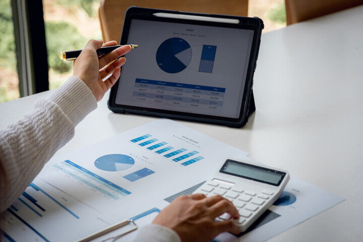 A man and a woman are reviewing documents with another man in a modern office space.